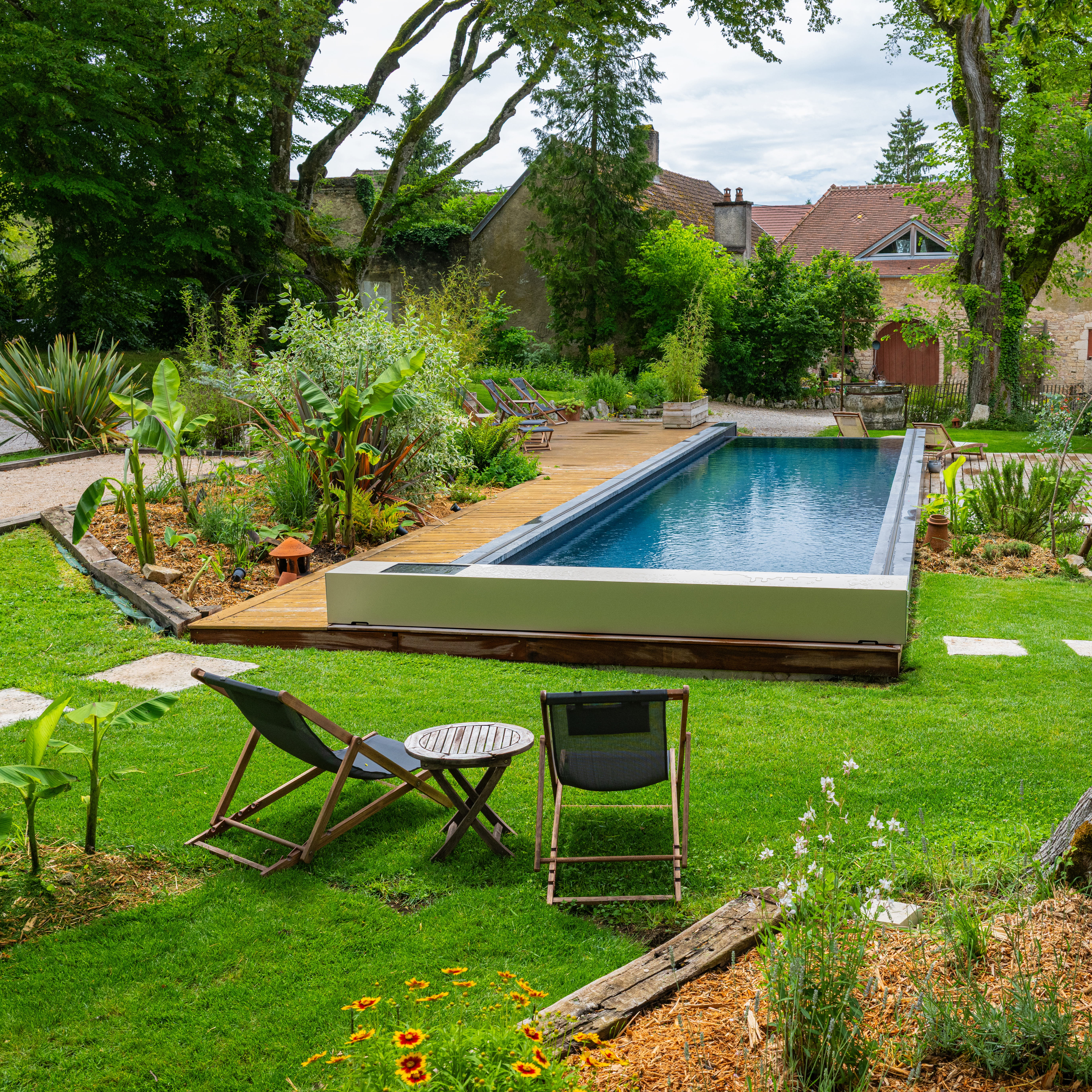 Piscine extérieure rectangulaire équipée d’une couverture Coverseal, intégrée à un jardin verdoyant avec terrasse en bois.
